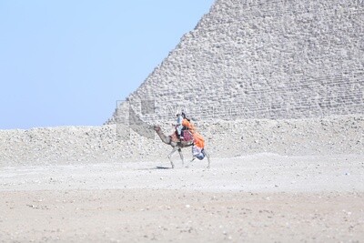An Egyptian man riding a camel with a tourist in the pyramids in Giza