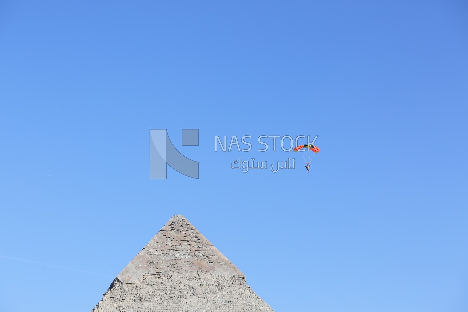 A person flying in the sky with a parachute next to the Great Pyramid in Egypt