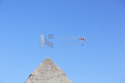 A person flying in the sky with a parachute next to the Great Pyramid in Egypt