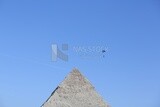 Person flying in the sky wearing a parachute over the Egyptian pyramids