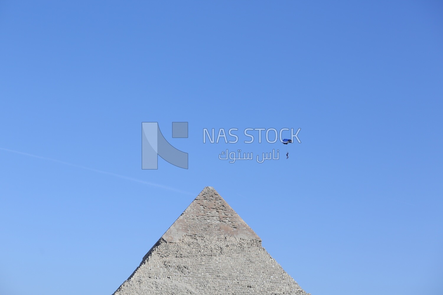 Person flying in the sky wearing a parachute over the Egyptian pyramids