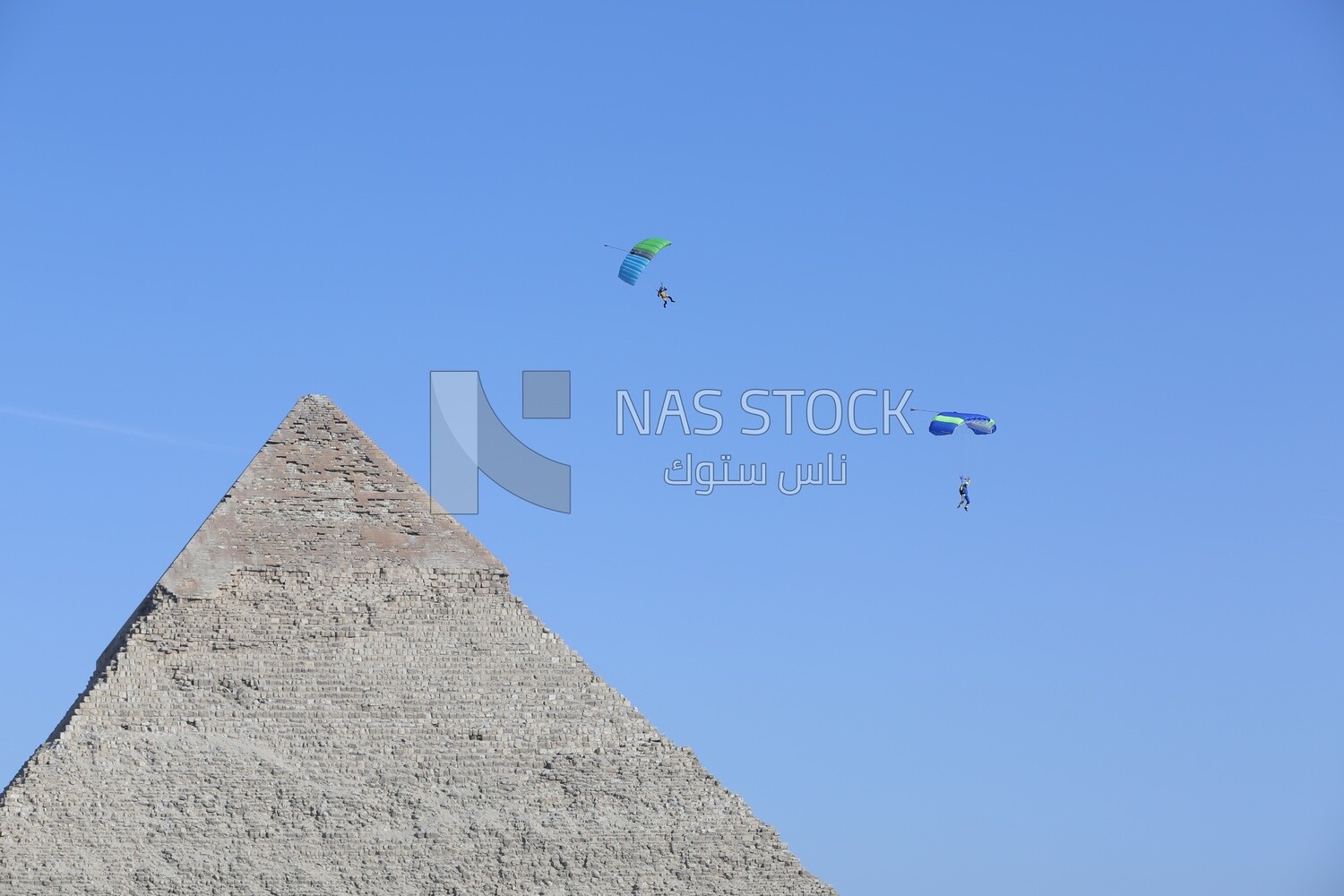 People flying in the sky wearing a parachutes over the Egyptian pyramids