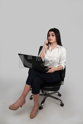 Photo of a businesswoman with formal wear sitting on a chair working on a laptop while talking on the phone, business development and partnerships, business meeting, Model