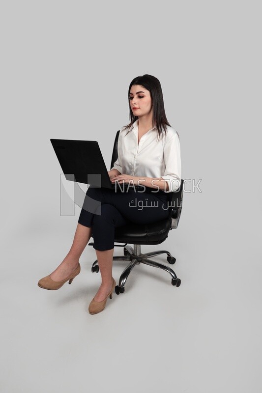 Photo of a businesswoman with formal wear sitting on a chair working on a laptop, business development and partnerships, business meeting, Model
