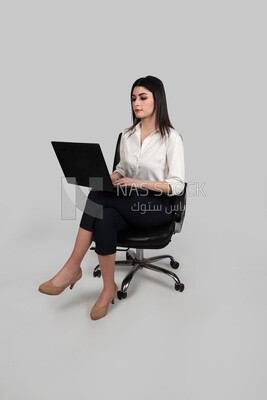 صورة سيدة أعمال ترتدي ملابس رسمية تجلس على كرسي وتعمل على كمبيوتر محمول ، وتطوير الأعمال والشراكات ، واجتماع عمل ، موديل