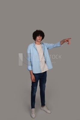young man with curly hair, wearing a shirt, and pointing to the right with his hand