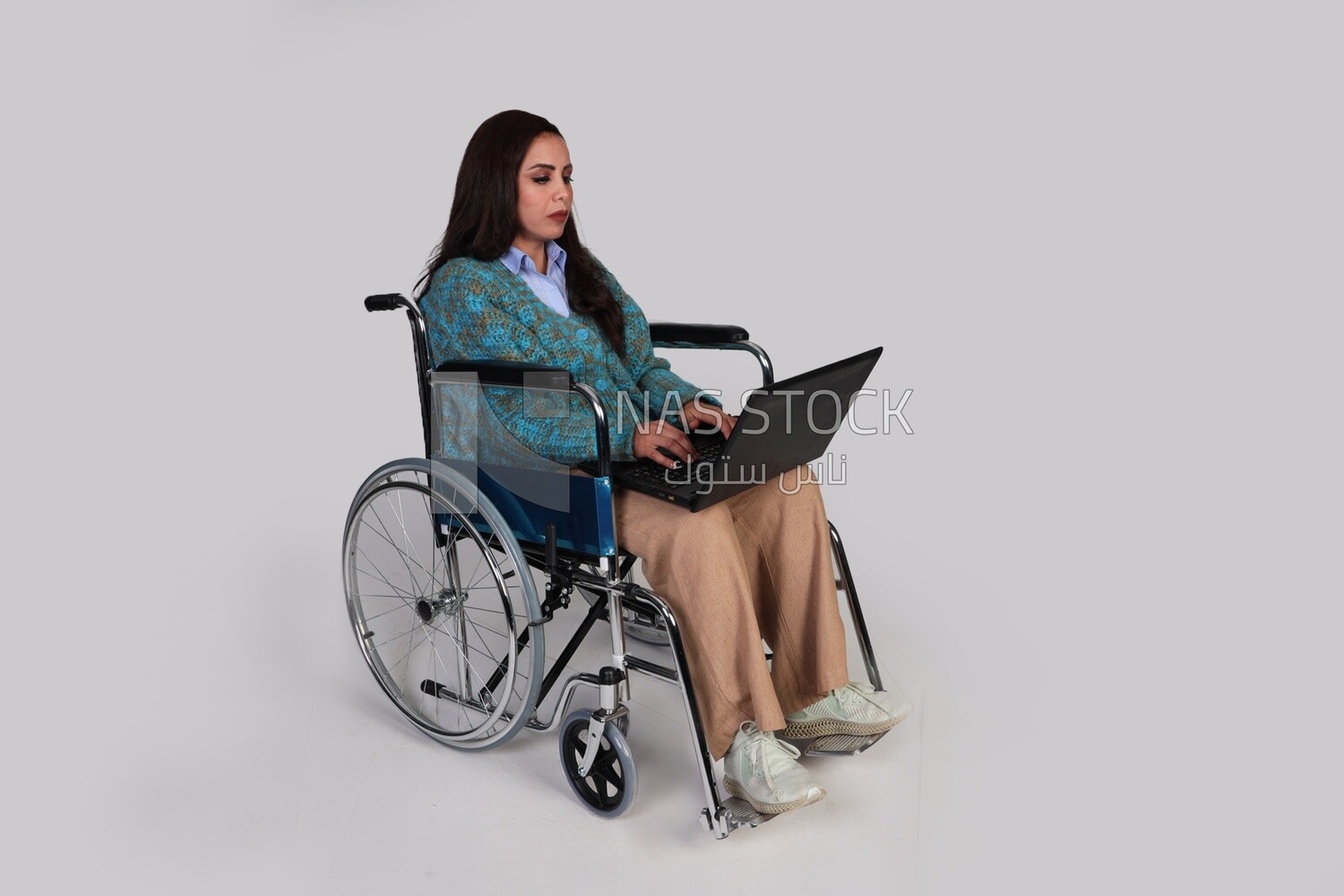 girl sitting in a wheelchair and working on a laptop