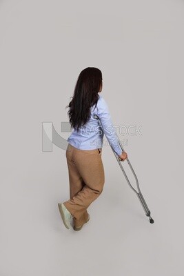 back view of a young woman with an injured leg walking with crutches, patient, medicine and health care concept, medical professions and jobs.