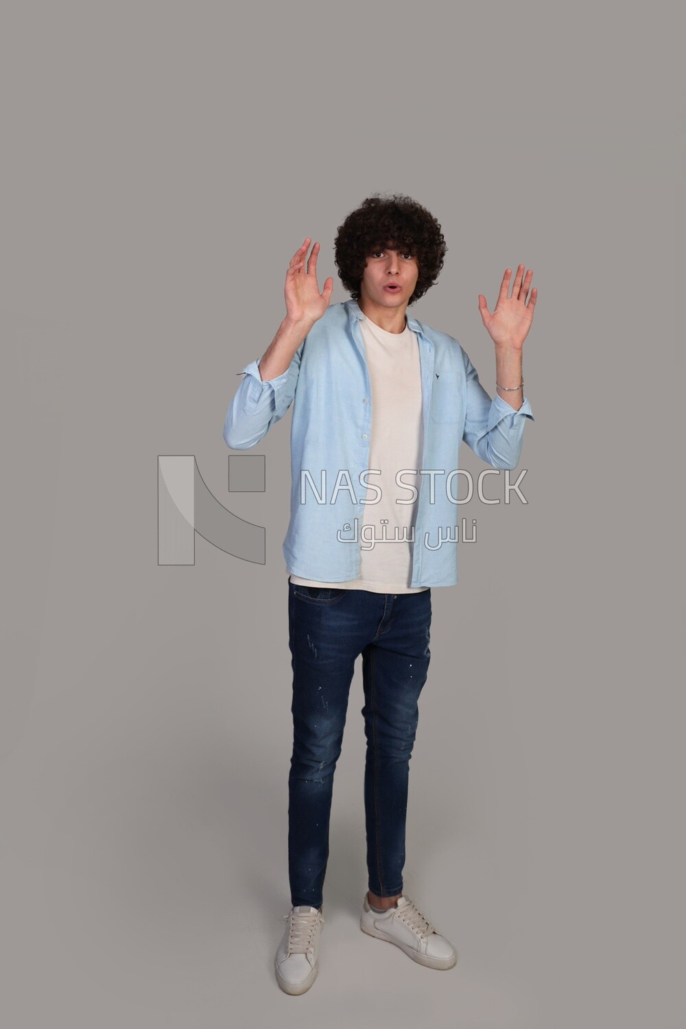 young man with curly hair standing amazed