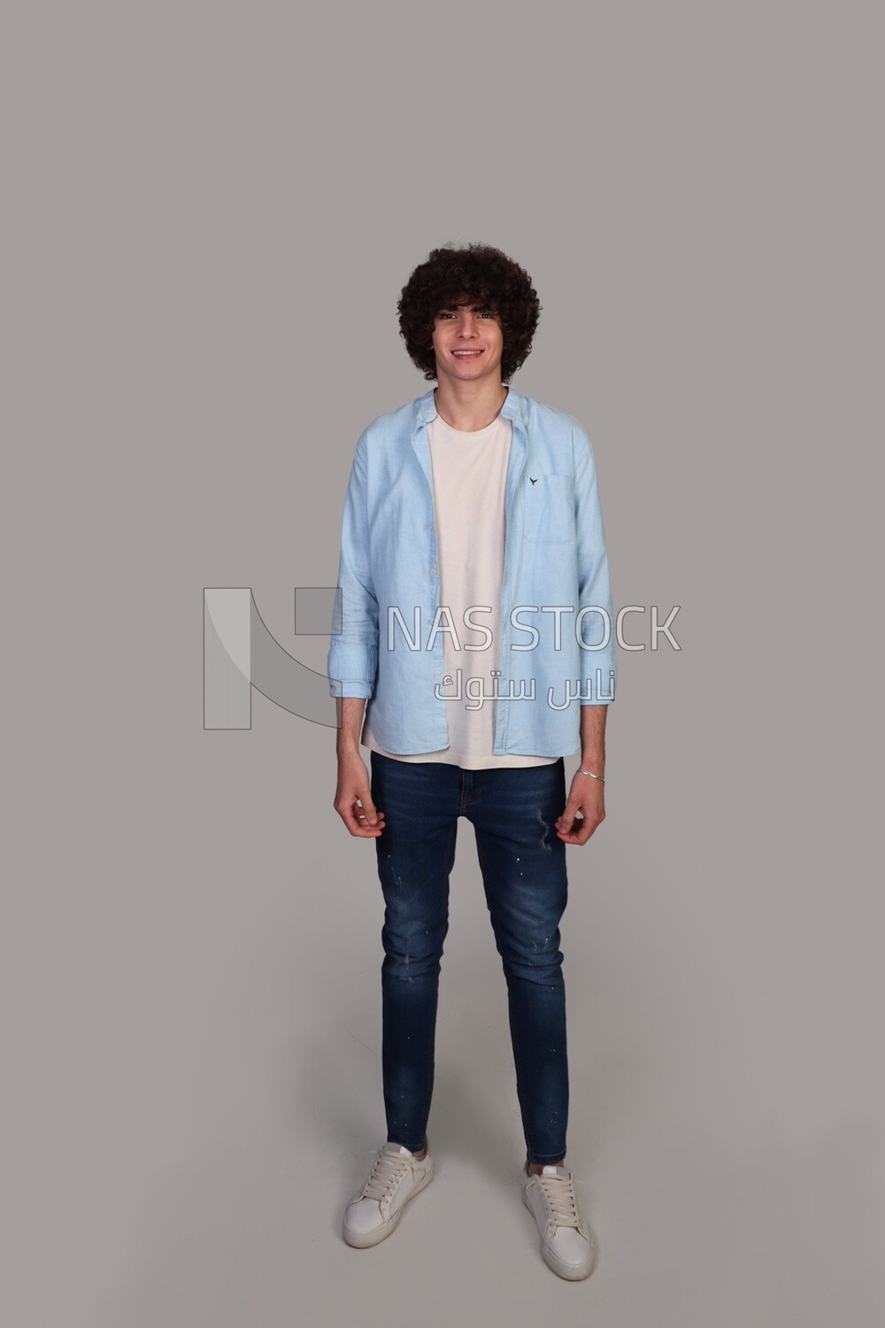 handsome young man with thick curly hair standing smiling
