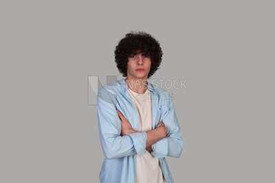 young man with curly hair wearing a shirt and holding his hand to his chest