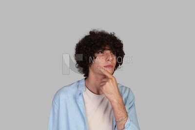 young man with curly hair looking up and thinking