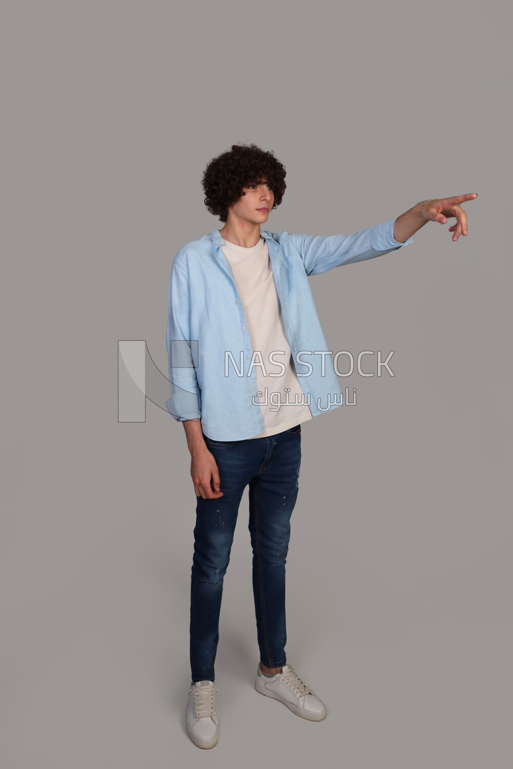 young man with curly hair, wearing a shirt, and pointing to the right with his hand