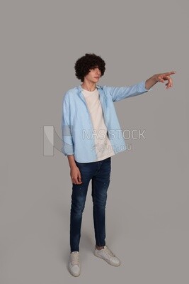 young man with curly hair, wearing a shirt, and pointing to the right with his hand