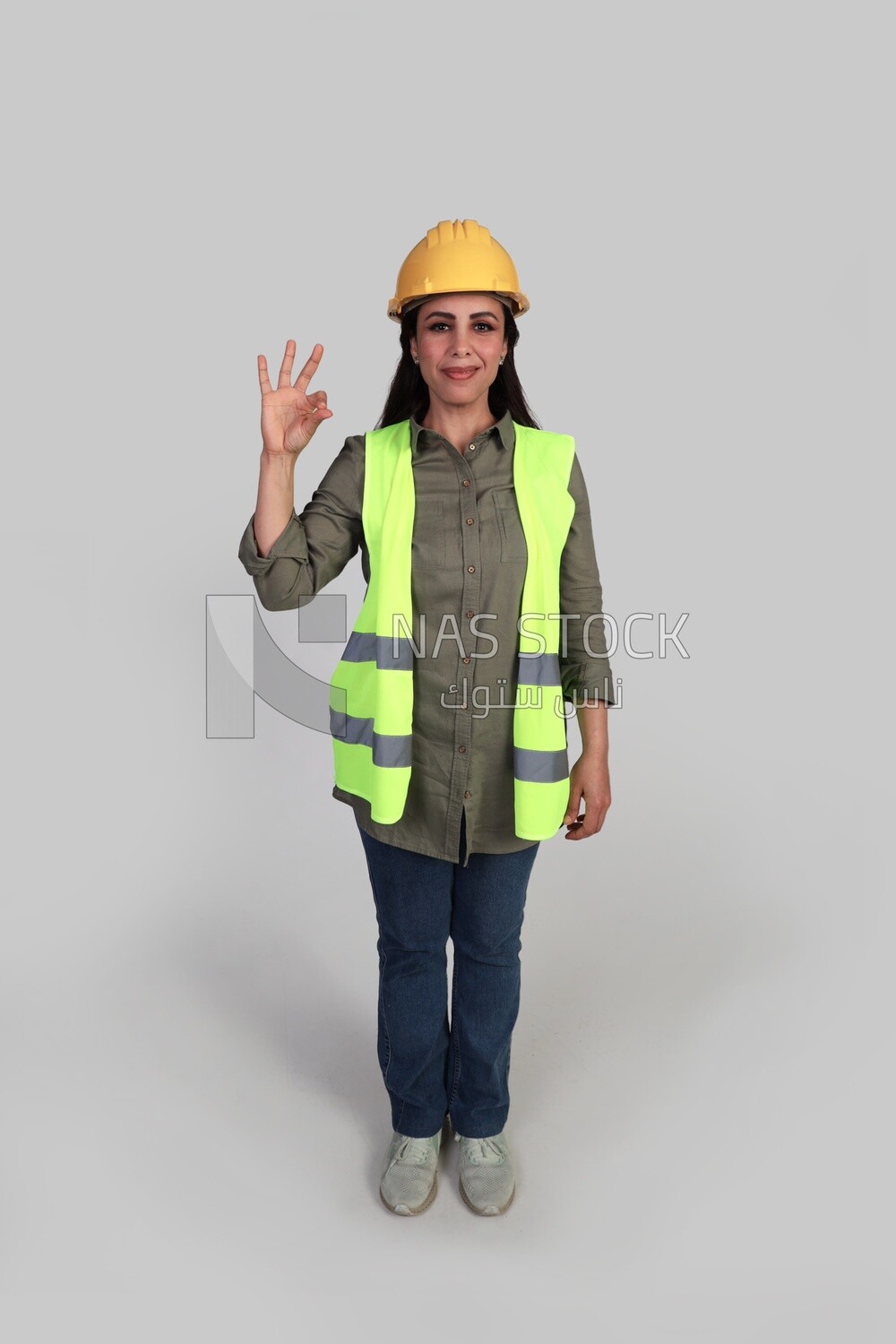 woman engineer hand gestures to express quality and distinction, a veiled construction engineer wearing a work safety suit, work helmet, wearing a mask for protection and prevention of viruses, formal