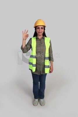 woman engineer hand gestures to express quality and distinction, a veiled construction engineer wearing a work safety suit, work helmet, wearing a mask for protection and prevention of viruses, formal