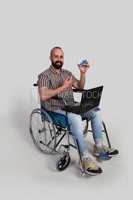 man sitting in a wheelchair with a laptop holding a credit card, patient, the concept of medicine and health care, an appointment to receive treatment in the hospital, emergency.
