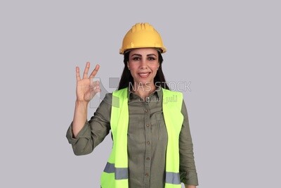 مهندسة إيماءات للتعبير عن الجودة والتميز ، مهندسة إنشاء محجبة ترتدي بدلة سلامة العمل ، خوذة العمل ، ترتدي قناع الحماية والوقاية من الفيروسات ، ملابس العمل الرسمية ، البناء