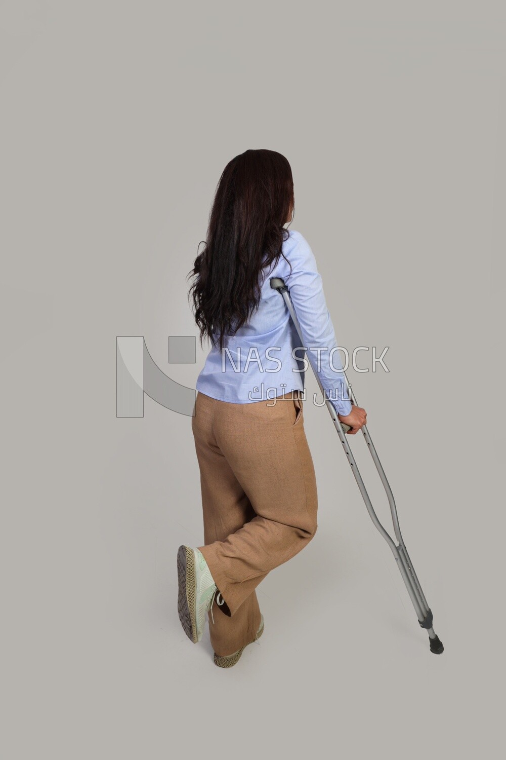 back view of a young woman with an injured leg walking with crutches, patient, medicine and health care concept, medical professions and jobs.