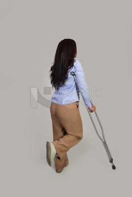 back view of a young woman with an injured leg walking with crutches, patient, medicine and health care concept, medical professions and jobs.