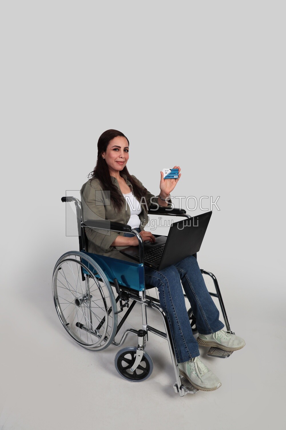 woman sitting in a wheelchair with a laptop and holding a credit card, patient, the concept of medicine and health care, an appointment to receive treatment in the hospital, emergency.