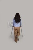 back view of a young woman with an injured leg walking with crutches, patient, medicine and health care concept, medical professions and jobs.