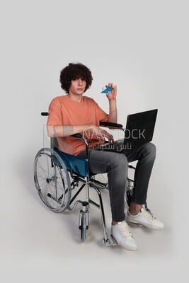 man sitting in a wheelchair with a laptop holding a credit card, patient, the concept of medicine and health care, an appointment to receive treatment in the hospital, emergency,  disabled people