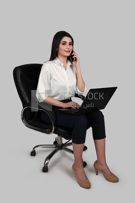 Photo of a businesswoman with formal wear sitting on a chair working on a laptop while talking on the phone, business development and partnerships, business meeting, Model