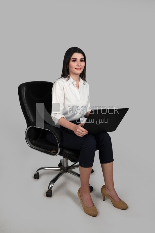 Photo of a businesswoman with formal wear sitting on a chair working on a laptop, business development and partnerships, business meeting, Model