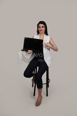Photo of a businesswoman with formal wear sitting on a chair holding a laptop, business development and partnerships, business meeting, Model