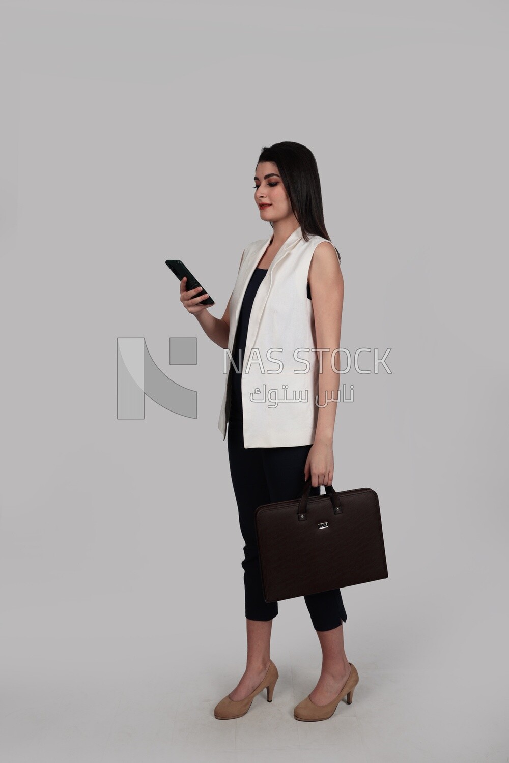 Photo of a businesswoman with formal wear holding a leather bag while checking the phone, business development and partnerships, business meeting, Model