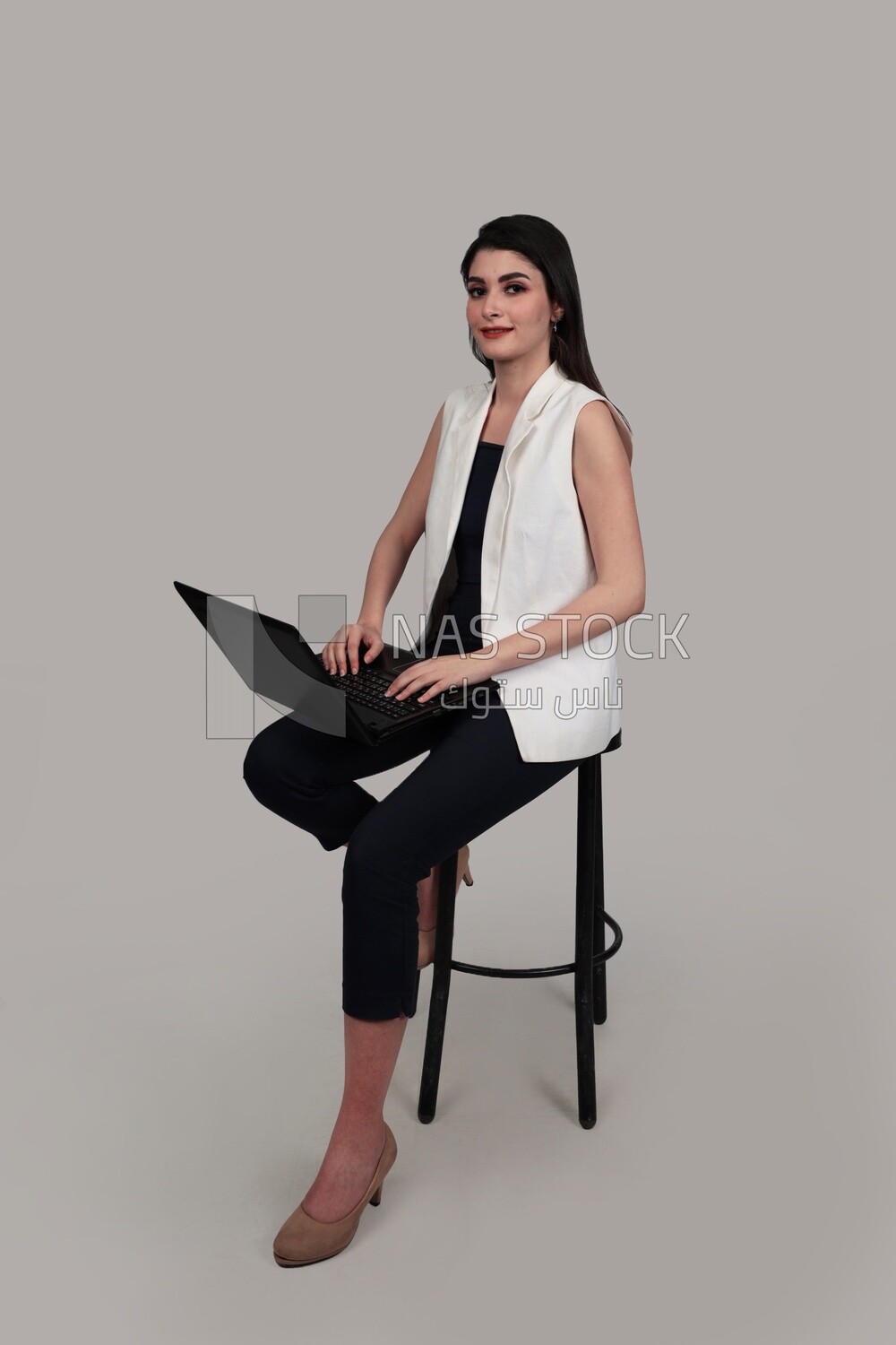 Photo of a businesswoman with formal wear sitting on a chair working on a laptop, business development and partnerships, business meeting, Model