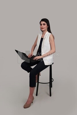 Photo of a businesswoman with formal wear sitting on a chair working on a laptop, business development and partnerships, business meeting, Model