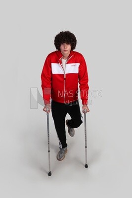 young man with a problem in his foot walking with crutches