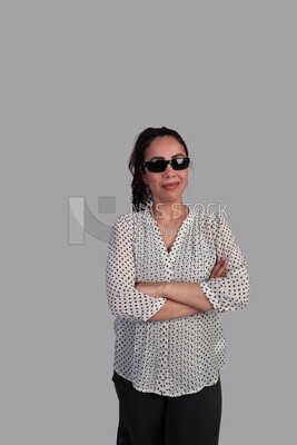 woman with her hair tied up, wearing sunglasses and holding her hand to her chest