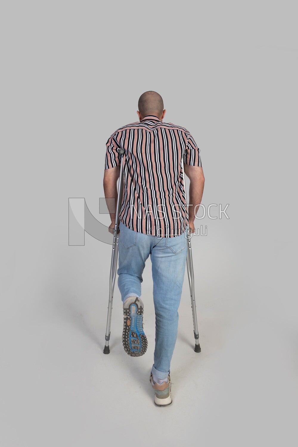 back view of a man with an injured leg walking with crutches, patient, medicine and health care concept, medical professions and jobs.