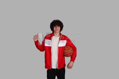 young man holding a basketball and raising a thumbs up