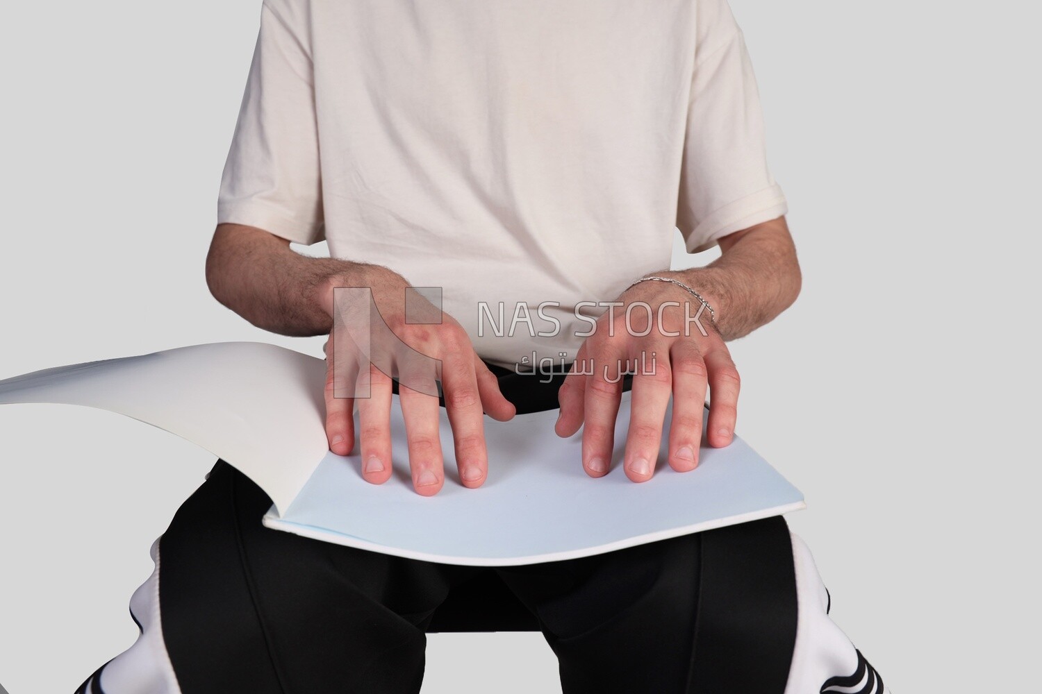 young man&#39;s hand reading a book in Braille