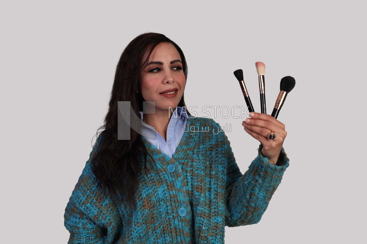 woman holding different shapes of makeup brushes