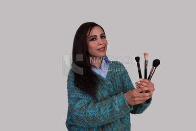 woman holding different shapes of makeup brushes