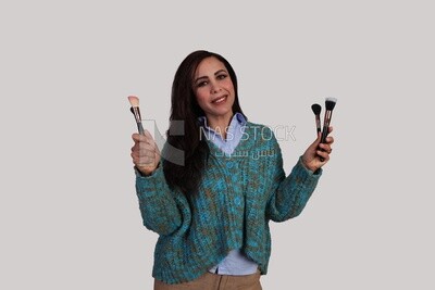 woman holding different shapes of makeup brushes