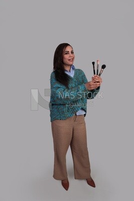 فتاة تمسك بفرشات الميك اب