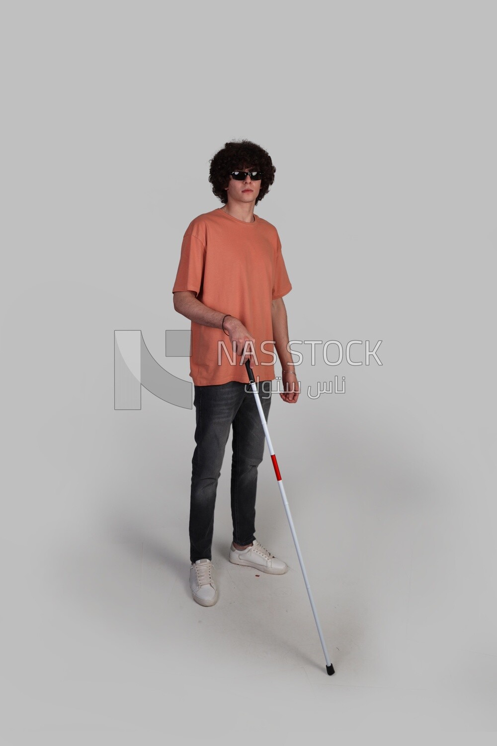 blind young man wearing glasses and holding a walking stick