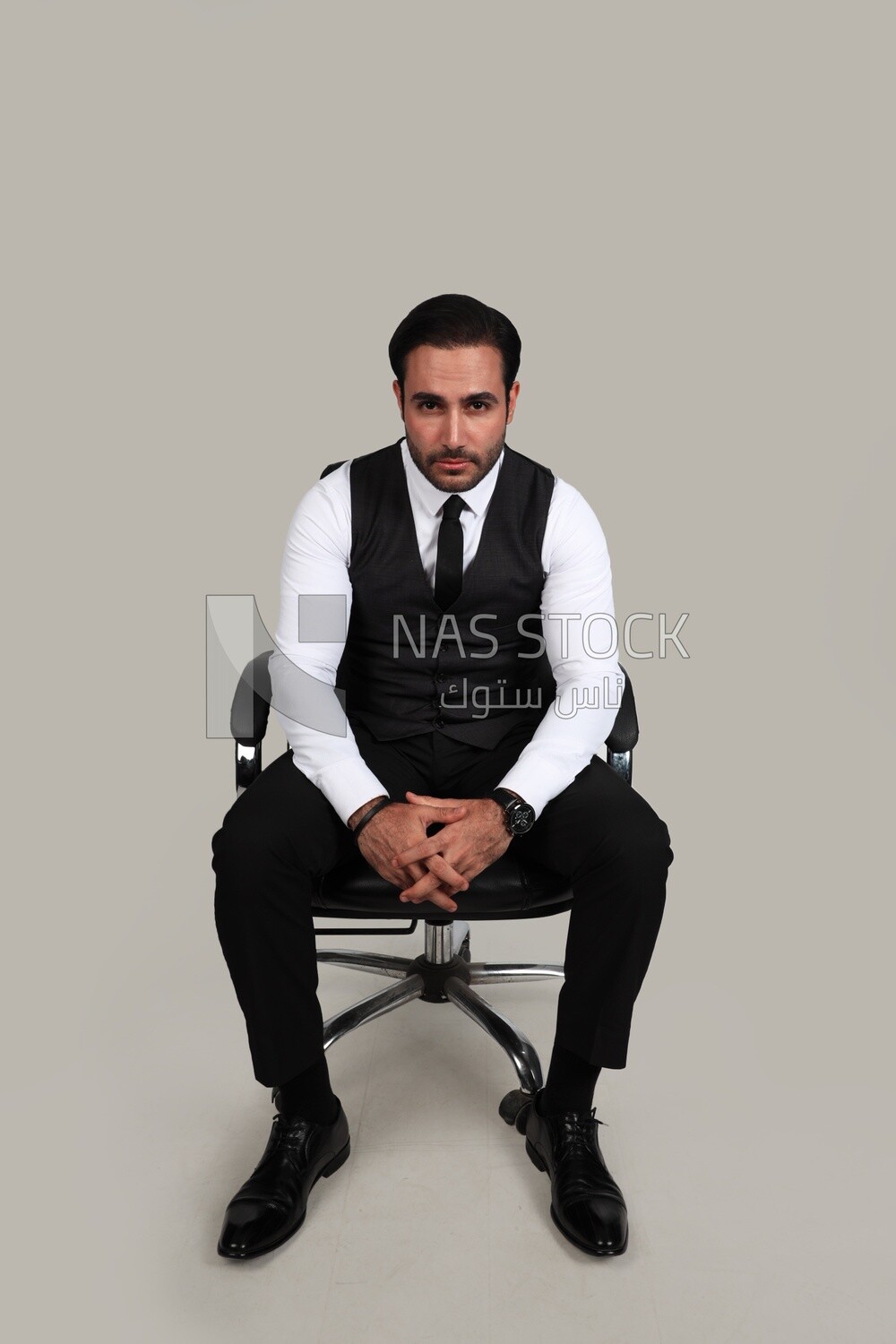 Photo of a businessman with a formal suit sitting on a chair and looking at the camera, business development and partnerships, business meeting, Model