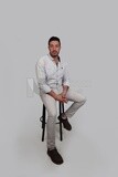 Photo Of a Handsome man sitting on a chair, Smiling Man, Wearing Casual Clothes Posing In a Light Room Interior, Smiling At the Camera, looking away