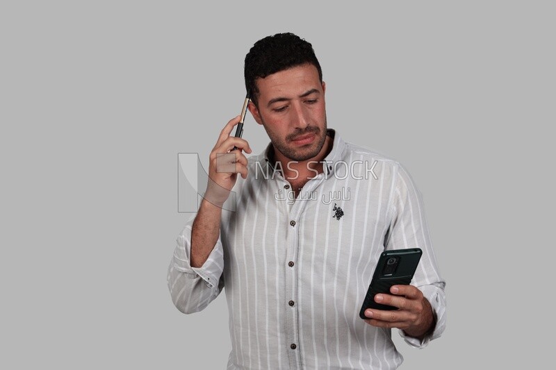 Photo Of a Handsome man standing and checking his mobile, Smiling Man, Wearing Casual Clothes Posing In a Light Room Interior, Smiling At the Camera, looking away