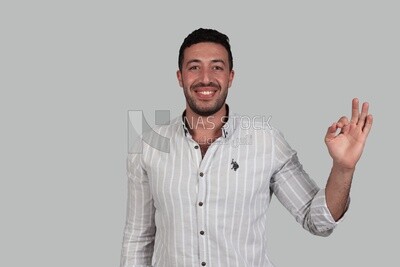 Photo Of a Handsome man with a hand gesture, Smiling Man, Wearing Casual Clothes Posing In a Light Room Interior, Smiling At the Camera, looking away