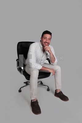 Photo Of a Handsome man sitting on a chair, Smiling Man, Wearing Casual Clothes Posing In a Light Room Interior, Smiling At the Camera, looking away