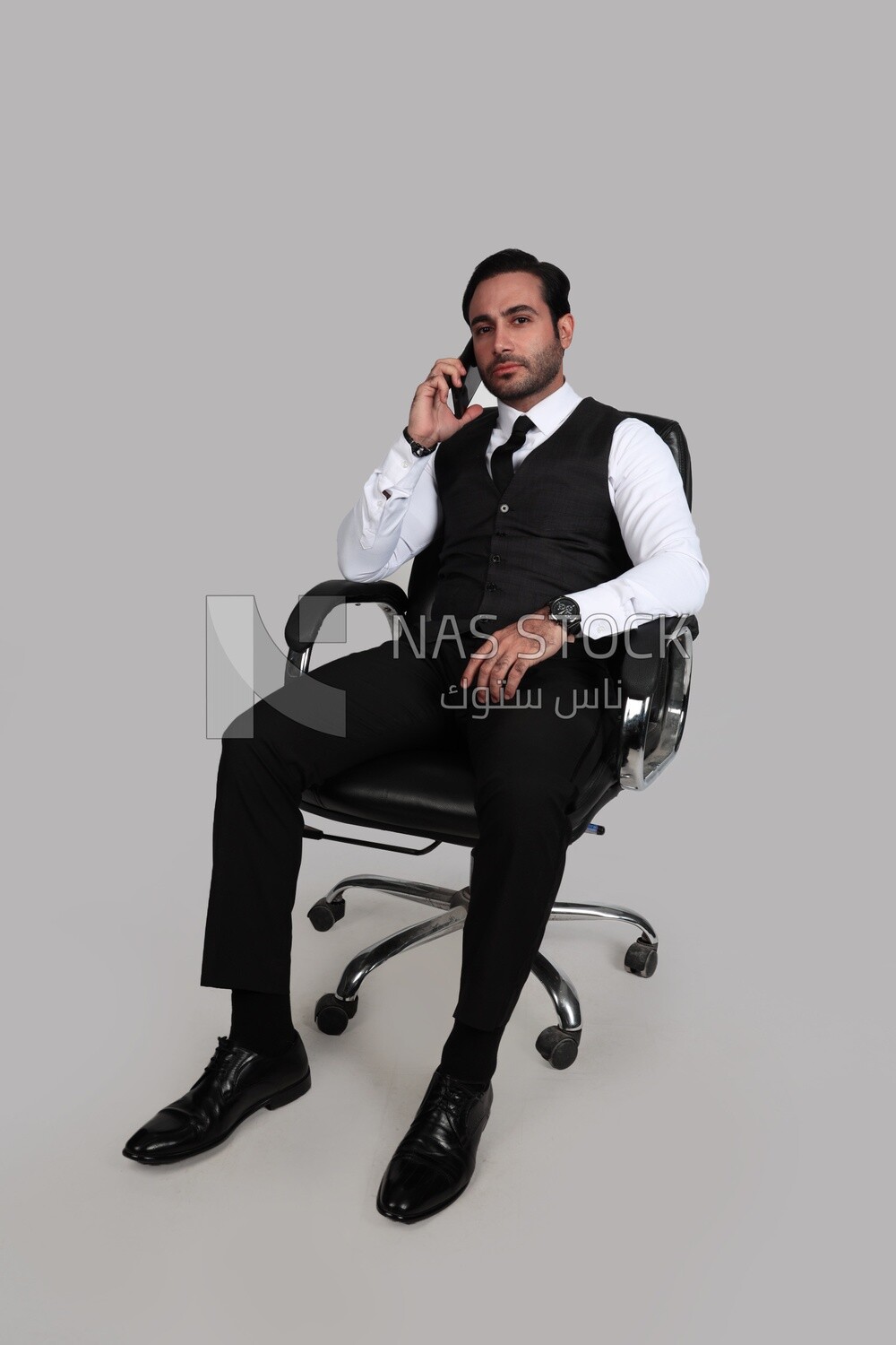 Photo of a businessman with a formal suit sitting on a chair and talking in his mobile phone, business development and partnerships, business meeting, Model