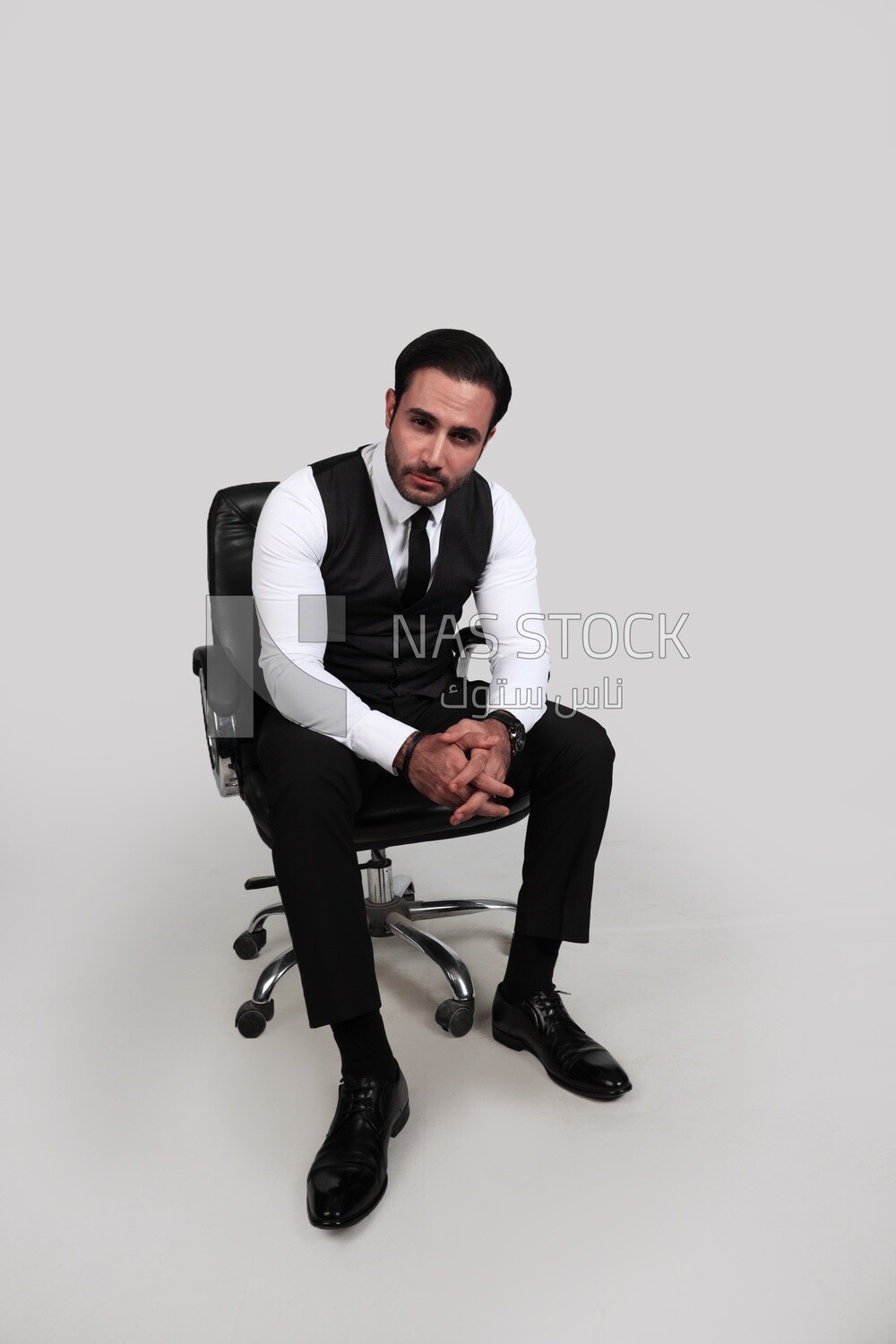 Photo of a businessman with a formal suit sitting on a chair and looking at the camera, business development and partnerships, business meeting, Model